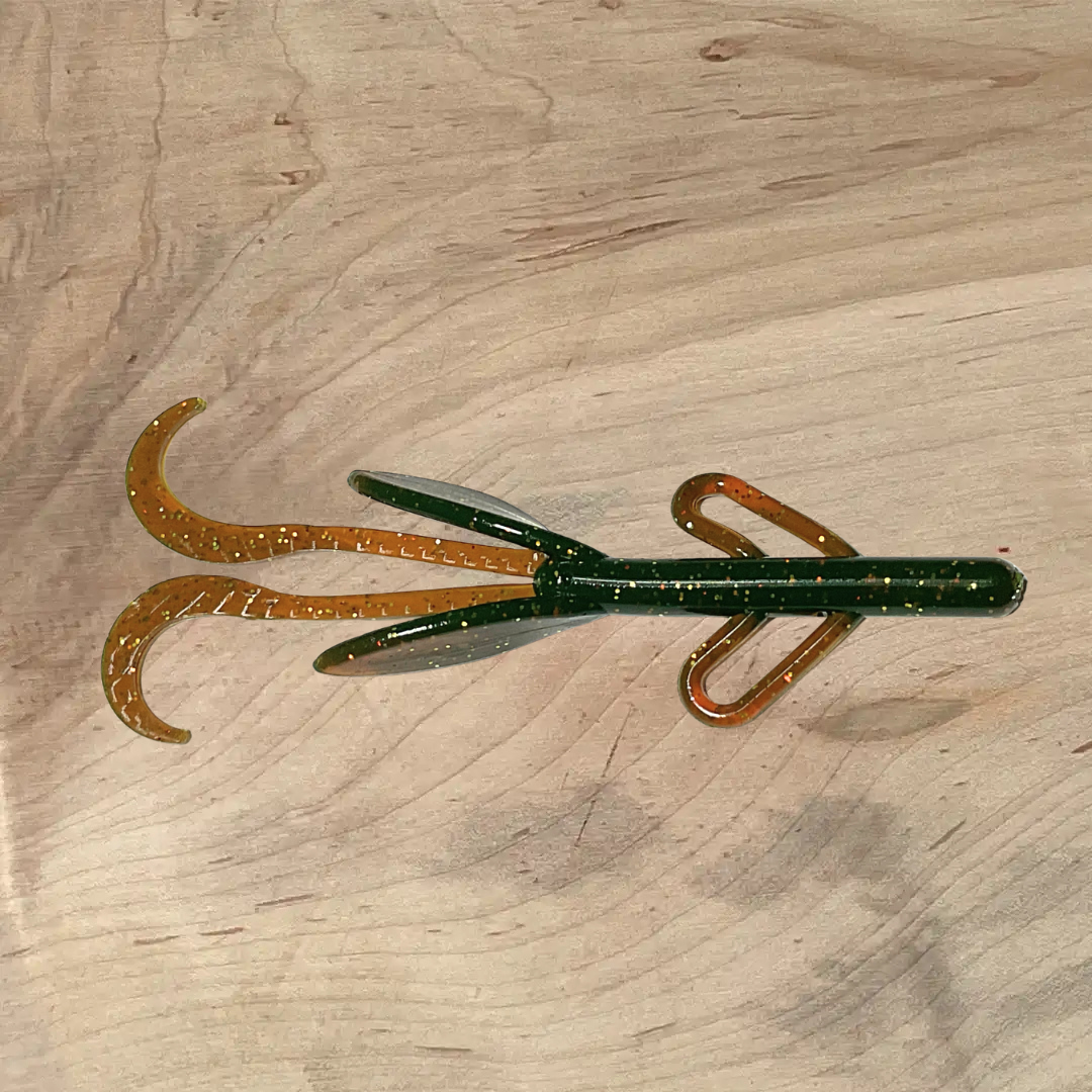 Brush Beater morning coffee lure displayed on wood surface, showcasing its green and brown color with glittered details.